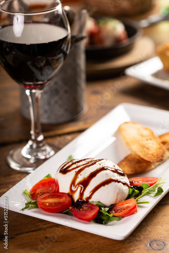 Burrata appetizer with balsamic glaze, tomatoes and toasted baguette photo