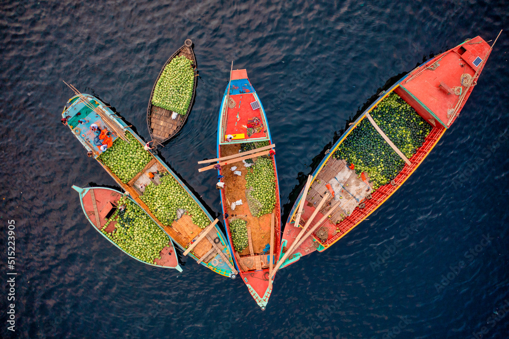 Aerial view of people working on commercial boats with fruits, Buriganga river, Keraniganj, Dhaka, Bangladesh.