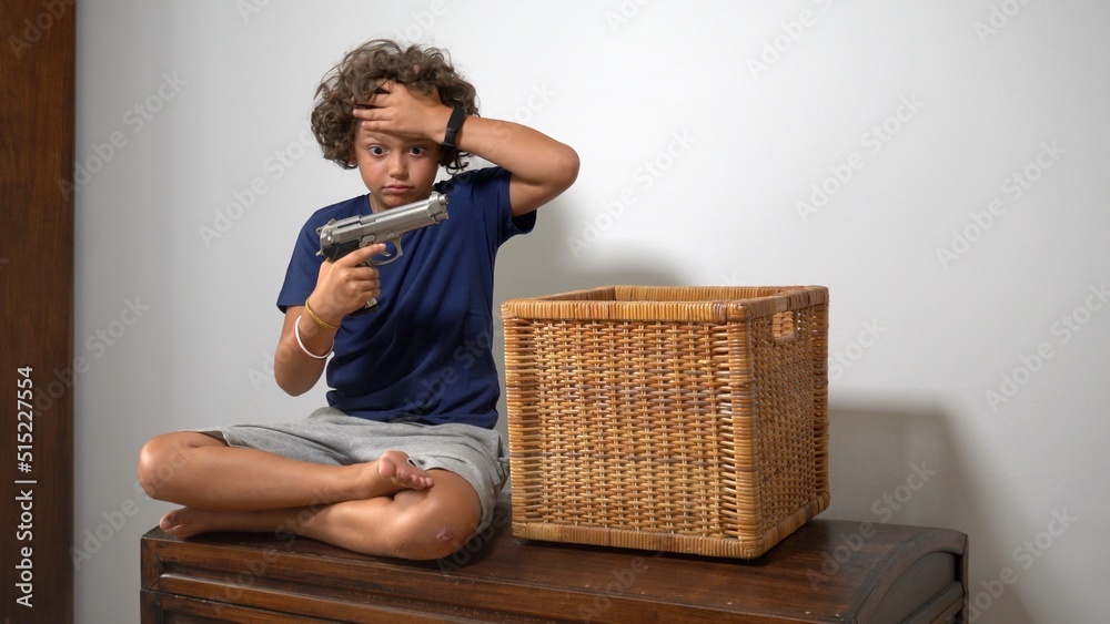 8-year-old boy alone at home finds a real gun in his parents' drawer - in America more and more children find guns in domestic places - social danger and violence