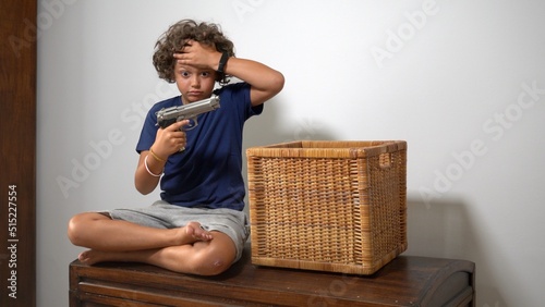8-year-old boy alone at home finds a real gun in his parents' drawer - in America more and more children find guns in domestic places - social danger and violence