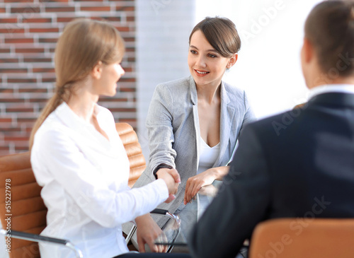 handshake of a Manager, and a client sitting behind a Desk