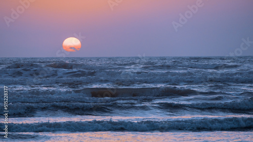 Fototapeta Naklejka Na Ścianę i Meble -  Egg Yolk Sunrise over the beach at North Padre Island; Texas, USA; Clouds in front of the sun
