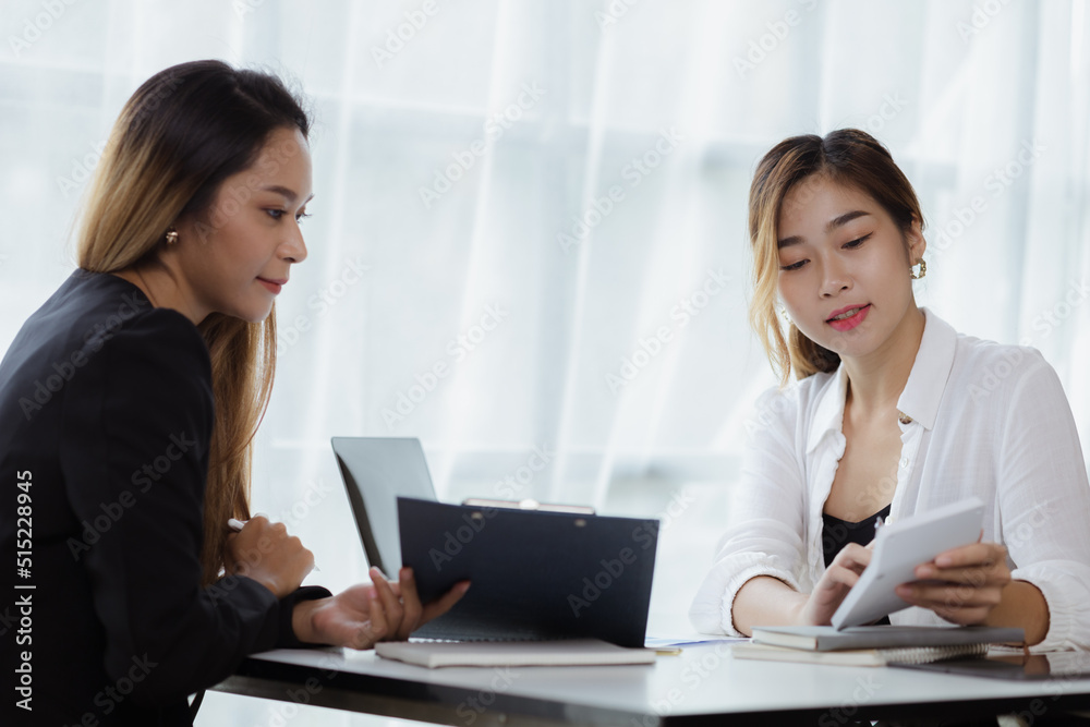Atmosphere in the office of a startup company, two female employees are discussing, brainstorming ideas to working on summaries and marketing plans to increase sales and prepare reports to managers. Atmosphere in the office of a startup company, two female employees are discussing, brainstorming ideas to working on summaries and marketing plans to increase sales and prepare reports to managers.