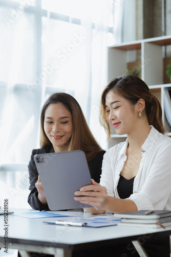 Atmosphere in the office of a startup company, two female employees are discussing, brainstorming ideas to working on summaries and marketing plans to increase sales and prepare reports to managers.