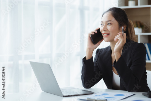 Asian woman talking on the phone, she is a salesperson in a startup company, she is calling customers to sell products and promotions. Concept of selling products through telephone channels.