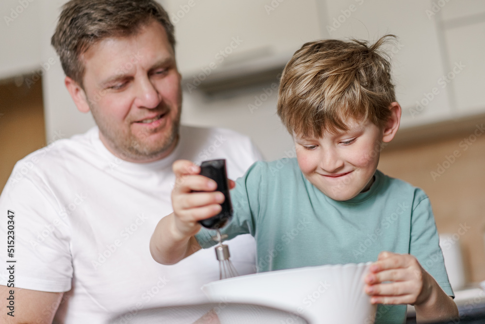 Dad and little son baking together in kitchen, preparing dough for pie, having fun at home, preparing a surprise for mom on mother's day Dad and little son baking together in kitchen, preparing dough for pie, having fun at home, preparing a surprise for mom on mother's day
