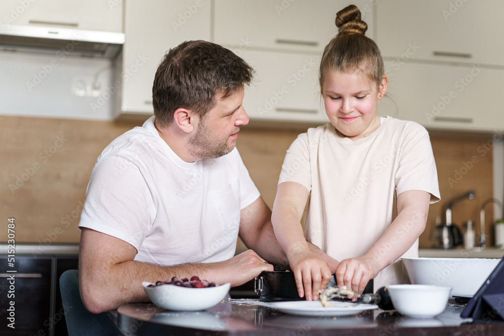 Dad and little daughter baking together in kitchen, preparing dough for pie, having fun at home during quarantine Dad and little daughter baking together in kitchen, preparing dough for pie, having fun at home during quarantine