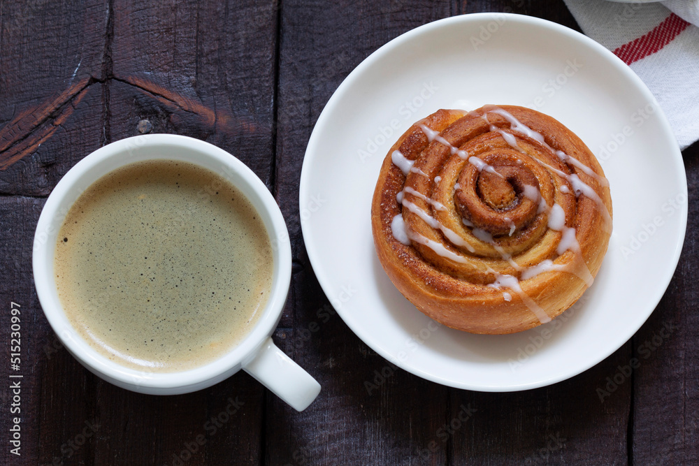 Cinnamon buns with icing served with coffee. Rustic style.