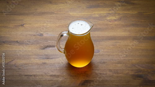 Full pitcher of beer close up on wooden table with copy space