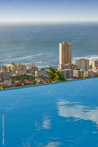 Scenic view of infinity swimming pool overlooking Sea Point in Cape Town, South Africa with ocean background. Luxury outdoor desk, rooftop feature in a condo, home, hotel. Cityscape, skyline of city