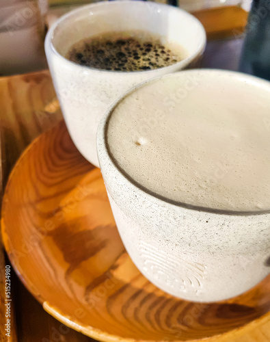 Cappuccino with fragrant milk foam and black Americano on a wooden tray. View from above. Coffee for two. Delicious freshly brewed coffee for breakfast in the cafe