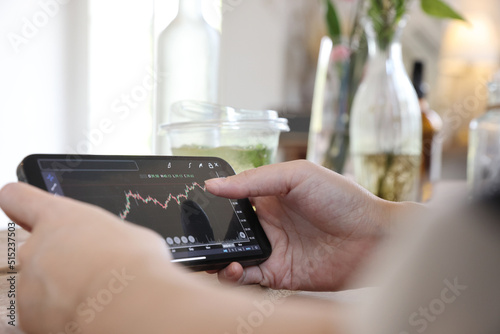 Woman hand using a smartphone for Stock exchange trading online in the coffee shop  business concept