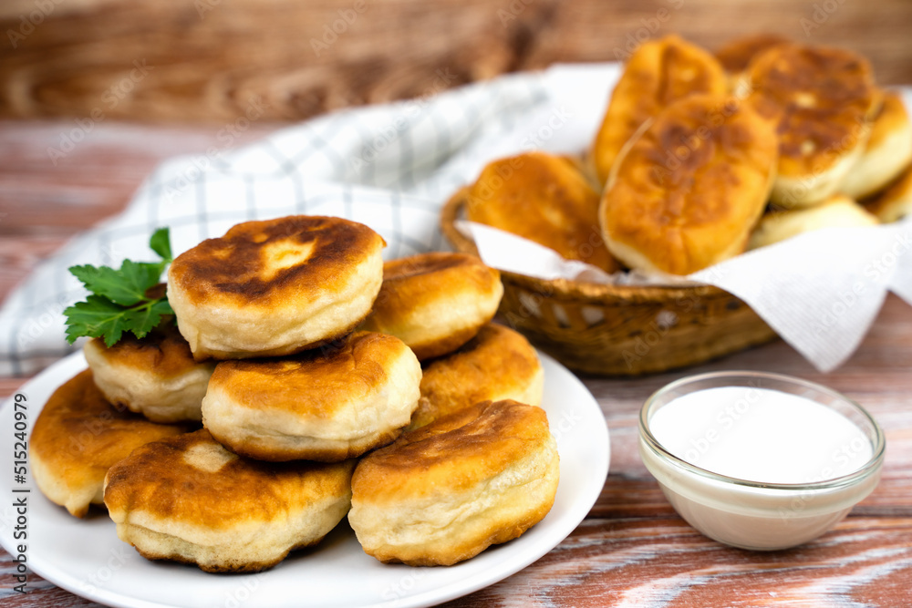 Hot fried pies with a filling on the wooden table. Close-up. Selective focus.