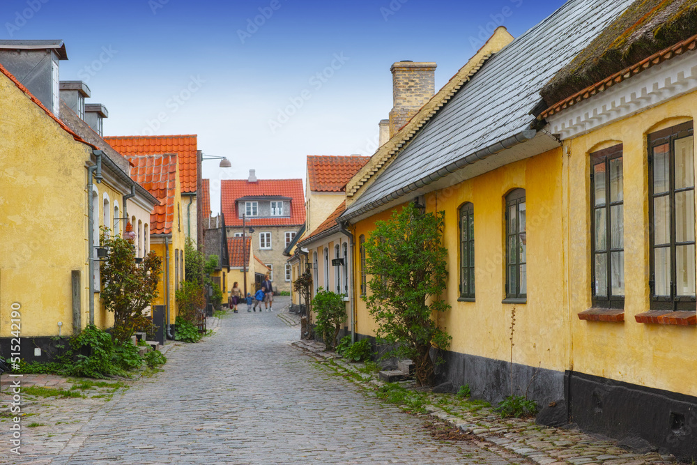 Old yellow houses located in Dragoer, Denmark. Tiny ancient houses in historical city. Alleys with yellow painted houses, red roofs, and cobblestone streets built in the traditional Danish style