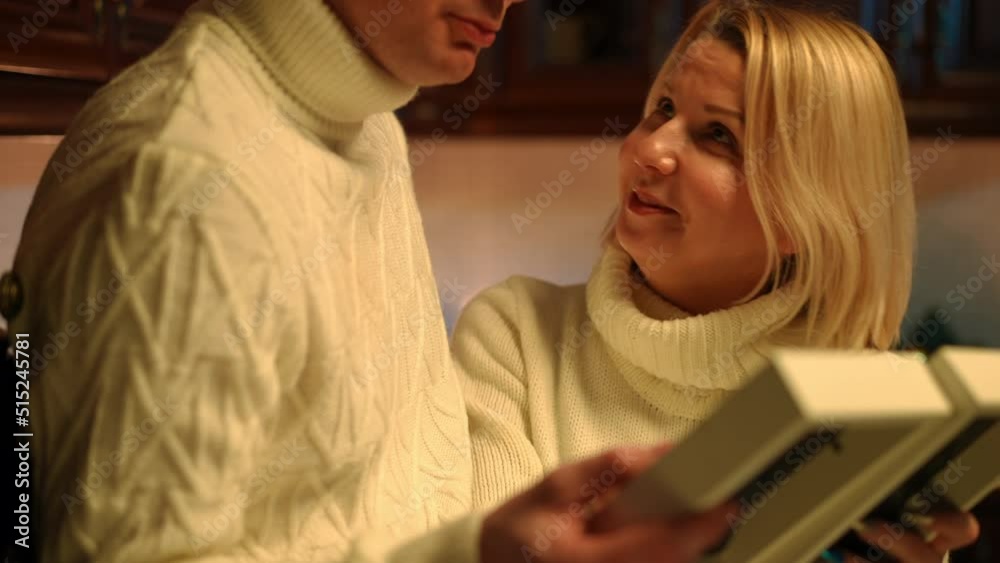 Portrait of beautiful adult woman discussing photos with unrecognizable man standing in kitchen at home. Positive plus-size Caucasian wife recalling memories with husband indoors on anniversary Portrait of beautiful adult woman discussing photos with unrecognizable man standing in kitchen at home. Positive plus-size Caucasian wife recalling memories with husband indoors on anniversary