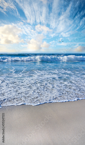 Sandy beach  sea  blue sky with clouds and copy space. Scenic seascape view of ocean waves washing on shore sand in a tropical resort with copyspace. Travel overseas  tourism abroad on summer holiday