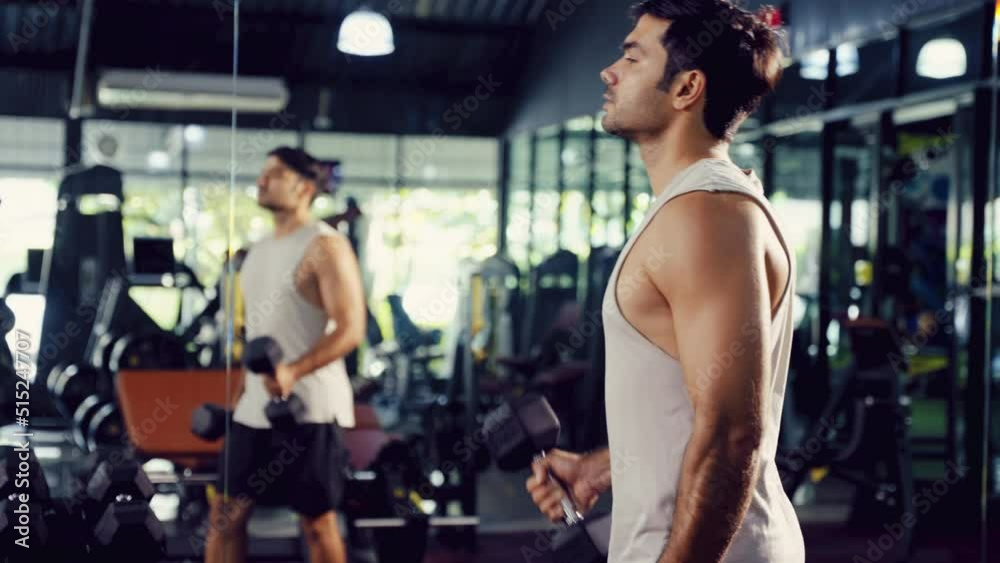 A Sport man lifting dumbbell at the mirror to motivate himself for body fit and firm, Active man with body building in the gym.