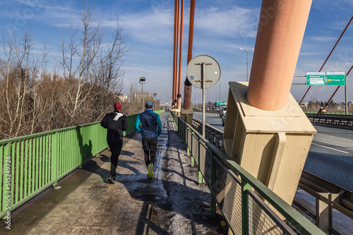 Joggers on Siekierkowski Bridge over River Vistula River in Warsaw city, Poland