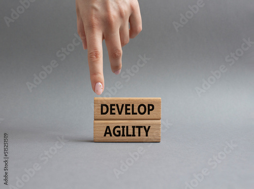 Develop agility symbol. Concept word Develop agility on wooden blocks. Beautiful grey background. Businessman hand. Business and Develop agility concept. Copy space