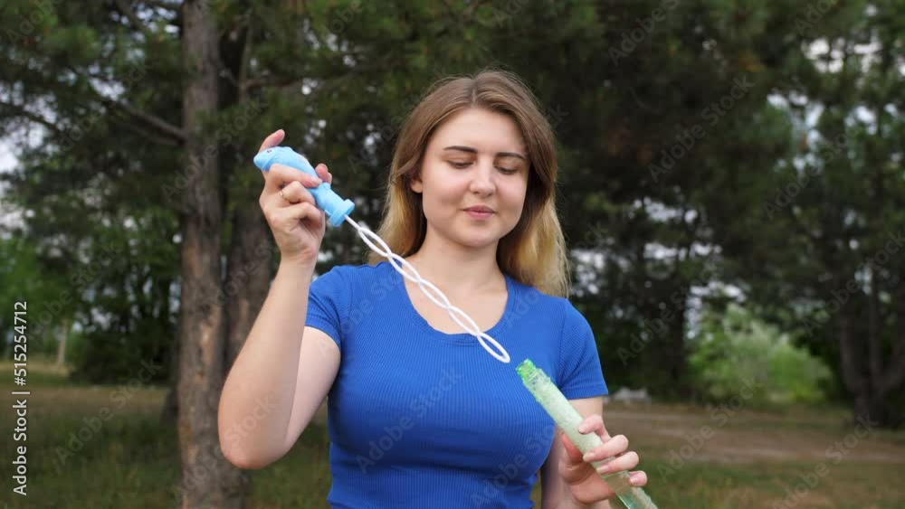 The girl blows bubbles. Soap bubbles on the background of the park. Happy Girl.