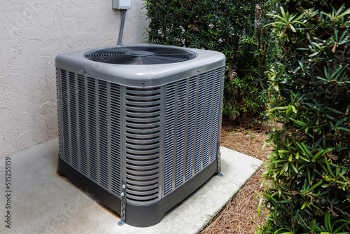 Modern HVAC air conditioner unit on concrete slab outside of house. photo