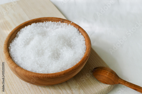 Sea coarse salt in a wooden bowl with a wooden spoon on the table. Rustic style. Natural resource. Salt is suitable for cooking and beauty treatments. Horisontal orientation. Copy space.