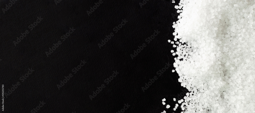 Obraz premium Banner. Black background, sprinkled with white sea salt. Rough texture. Salt is suitable for cooking and beauty treatments. Horizontal orientation. Top view. copy space