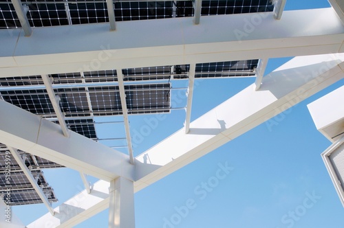 Architectural view of white beams and solar panels against blue sky © David