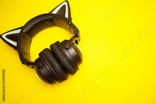 Black wireless headphones isolated on yellow background. A cosplay accessory. Wireless gaming headset with a cat ear. With backlight. Front View