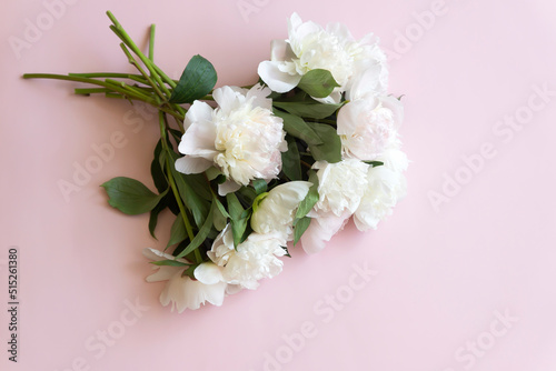 Cup of coffee and white peonies on a wooden background. Top view, copy space.