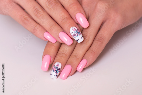 Beautiful female hands with creative manicure nails with unicorn design  pink gel polish 