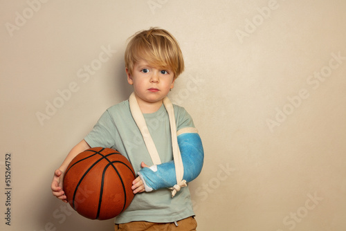Sad crying little blond boy with basketball ball