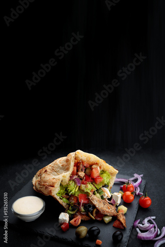 Pita with meat and sauce, on a black background