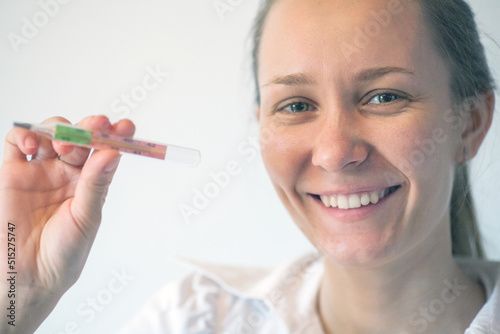 Woman being sick having flu looking at temperature on thermometer.