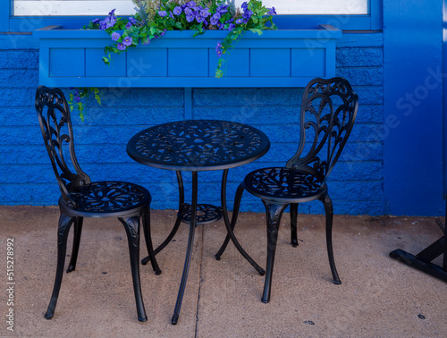 Black Wrought Iron Chairs and Table outside a Street Cafe.
