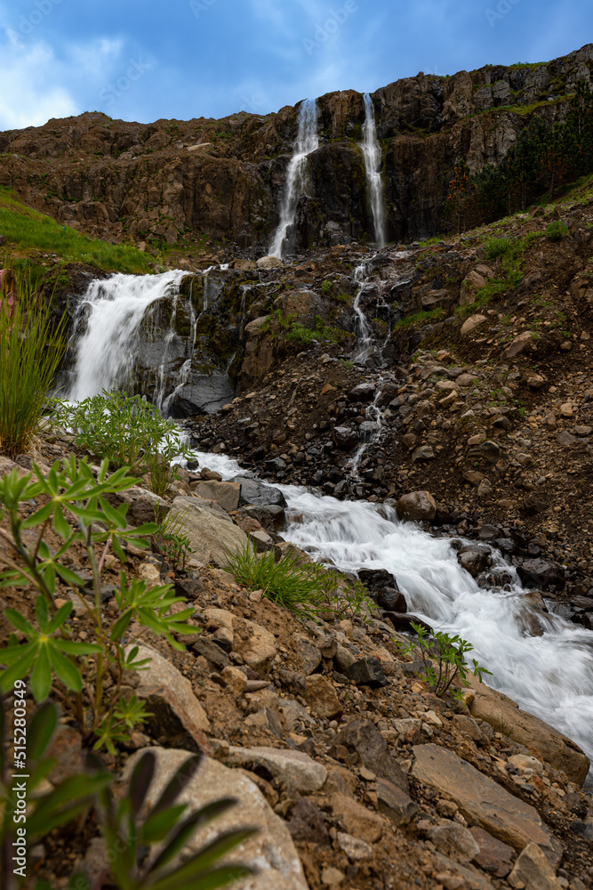 Melting glaciers near the town of Seydisfjordur in Iceland create small waterfalls that flow around stones and vegetation. Melting glaciers near the town of Seydisfjordur in Iceland create small waterfalls that flow around stones and vegetation.