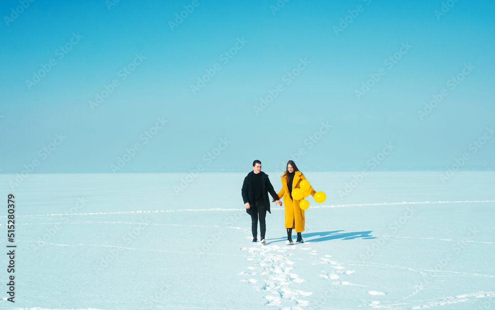 Happy walking couple. In love man and woman walking on the snowy ice. Winter vacation concept. Happy Valentines day concept. Happy walking couple. In love man and woman walking on the snowy ice. Winter vacation concept. Happy Valentines day concept.