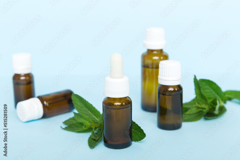 Natural Mint Essential Oil in a Glass Bottle. organic cosmetics with herbal extracts of mint on colored background Natural Mint Essential Oil in a Glass Bottle. organic cosmetics with herbal extracts of mint on colored background