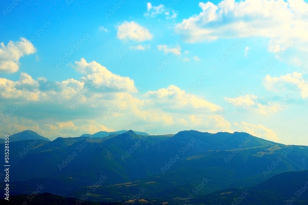 Clear shot with an impressive view at the raw sibillini mountains summits standing tall and reaching a paradisiacal azure sky with creamy clouds