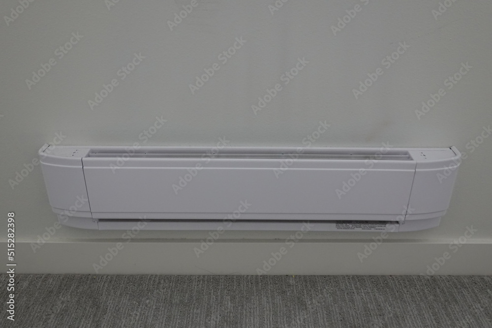 Baseboard heater on the white wall and carpet Floor. Baseboard heater on the white wall and carpet Floor.