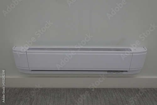 Baseboard heater on the white wall and carpet Floor.
