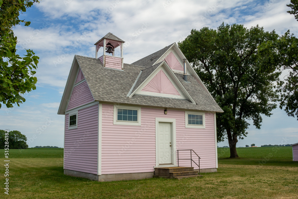 Close up view of an old pink country school house exterior with bell tower, built in the 1800’s in the midwestern USA