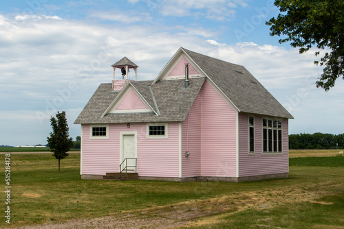 Close up view of an old pink country school house exterior with bell tower, built in the 1800’s in the midwestern USA