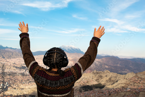 Traveler woman listening to a podcast, Person traveling listening to music. Free space and nature. Concept of a woman with her hands up happy and content listening to an audio playlist. La Paz, Bolivi photo