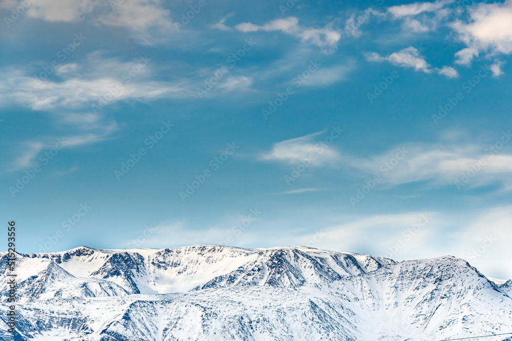 Fototapeta premium Snowy top of mountain range under blue sky