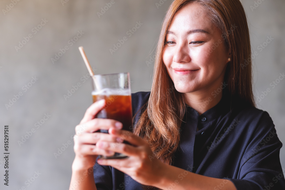 Portrait image of a beautiful young asian woman holding and drinking iced coffee Portrait image of a beautiful young asian woman holding and drinking iced coffee