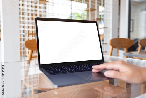 Mockup image of a woman working and touching on laptop touchpad with blank white desktop screen in cafe