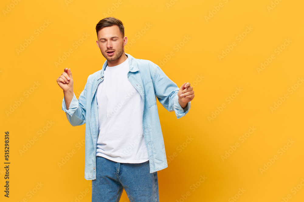 Happy relaxing tanned handsome man in blue basic t-shirt dance enjoy cool day posing isolated on orange yellow studio background. Copy space Banner Mockup. People emotions Lifestyle concept Happy relaxing tanned handsome man in blue basic t-shirt dance enjoy cool day posing isolated on orange yellow studio background. Copy space Banner Mockup. People emotions Lifestyle concept