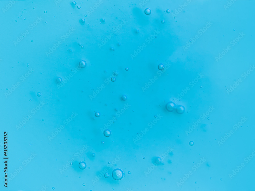 Texture of transparent antiseptic gel with air bubbles on blue background. Summer ocean imitation. Concept of skin moisturizing, prevention of virus. Liquid beauty product closeup. Backdrop, flat lay