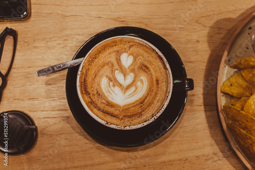 Vista superior de taza de café con leche, con dibujo artístico de flor en la espuma  photo